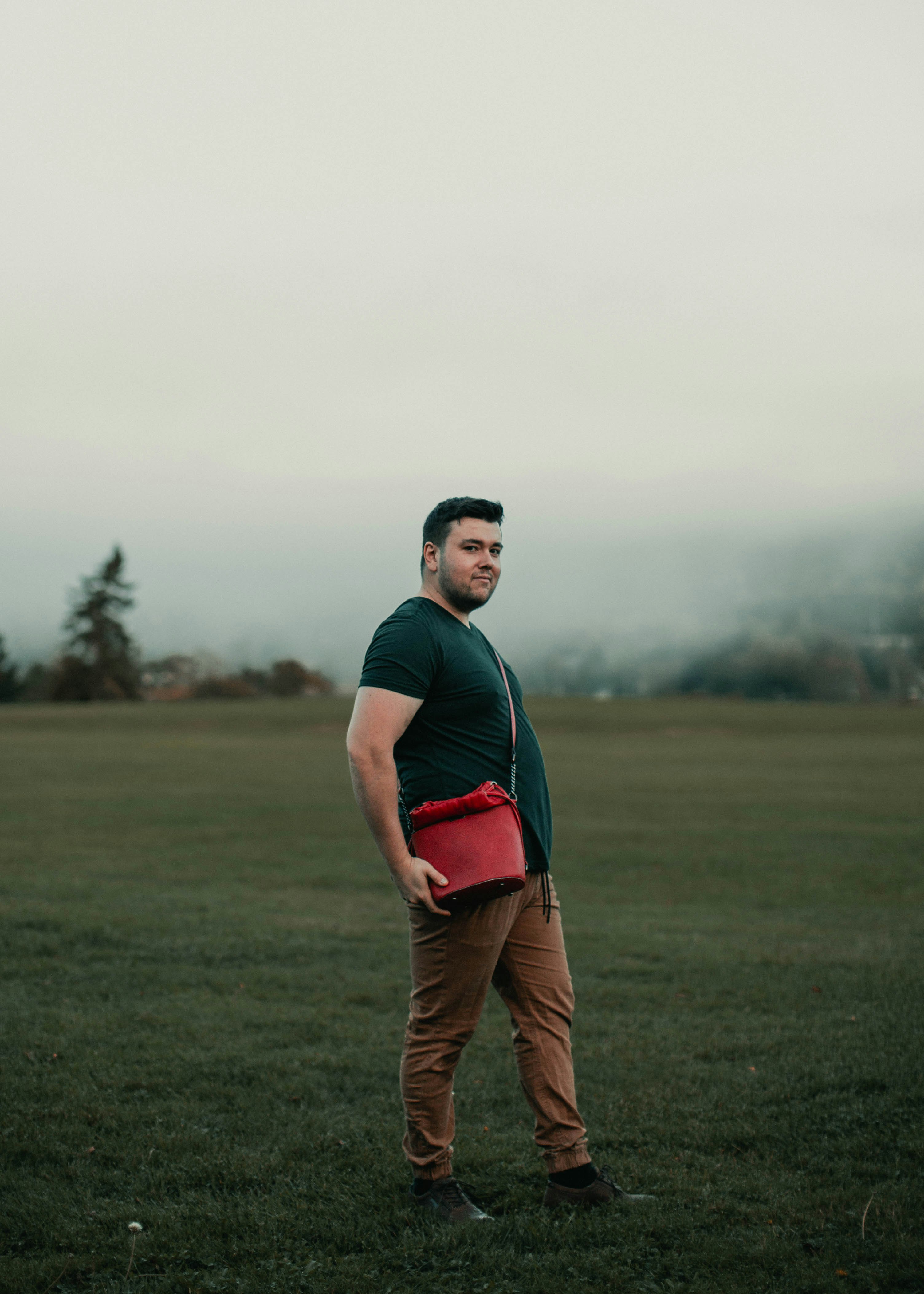 man in black crew neck t-shirt and brown pants standing on green grass field during